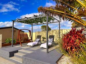 um pátio com 2 cadeiras e uma pérgola em Sunny Shores House with Private Pool em Lake Illawarra