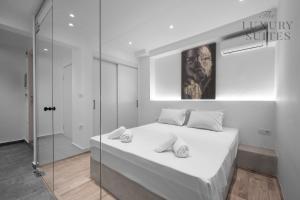 a white bedroom with a bed and a glass shower at Maison Cristal, The Luxury Suites in Thessaloniki