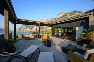 a patio with tables and chairs with mountains in the background at Hotel Riviera in Riva del Garda