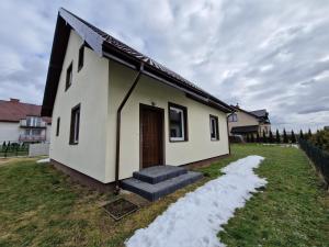 mały biały dom ze śniegiem na dziedzińcu w obiekcie Domki na Kaszubach w mieście Bukowina