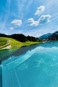 einen Pool mit Blick auf einen Golfplatz in der Unterkunft ALMMONTE PRÄCLARUM SUITES Design Hotel in Wagrain