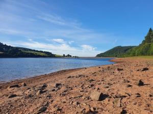 a sandy beach with a body of water and trees at Ty Carreg cottage, Bwlch, Brecon in Brecon