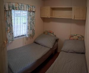 two beds in a small room with a window at Domek Letniskowy Kołczewo in Kołczewo