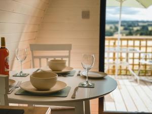 a table with plates and wine glasses on a porch at Jerusalem Farm Pods in Tranent