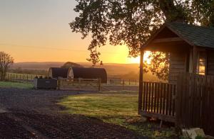 a cabin with a fence and the sunset in the background at Jerusalem Farm Pods in Tranent