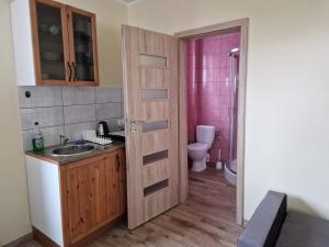 łazienka z umywalką, toaletą i drzwiami w obiekcie Domki na Kaszubach w mieście Bukowina