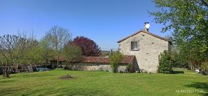 an old stone house with a grass yard in front of it at La maison de Marie in Verteuil-sur-Charente