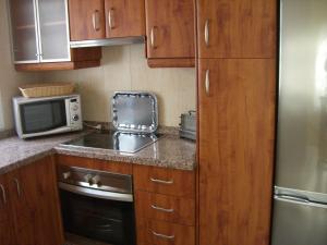 a small kitchen with wooden cabinets and a microwave at Playa Golf in Benalmádena