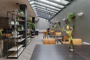 a dining room with tables and chairs and plants at Hotel de Duif Lisse - Schiphol in Lisse