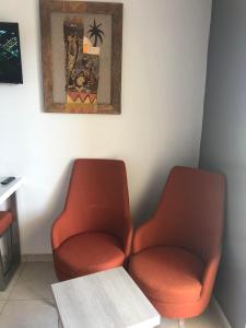 2 orangefarbene Stühle in einem Zimmer mit einem Tisch in der Unterkunft Eden Star Resort in Zarzis