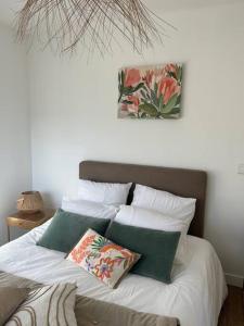 łóżko z białą pościelą i zielonymi poduszkami w obiekcie Les Cottages de Carine w mieście Saint-Marcel +37 zdjęć
