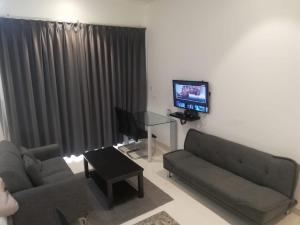 a living room with two couches and a flat screen tv at Hawana Salalah Laguna Studio in Salalah