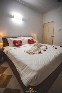 a bedroom with a large white bed with roses on it at Bright Waves Villa in Bentota