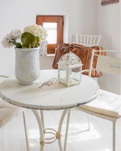 een witte tafel met een vaas met bloemen en een tafel met een lamp bij Domo 'e sa rosa in Bosa