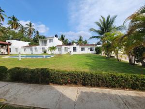una casa con un gran patio con palmeras en Casa Amarilla, en Zihuatanejo