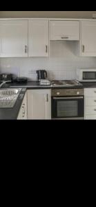 cocina con armarios blancos y fogones en Village view apartments en Tynemouth