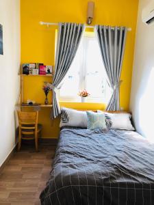 a bedroom with yellow walls and a bed with a window at HD House Homestay Vũng Tàu in Vung Tau