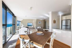 cocina y sala de estar con mesa de madera y sillas en Tranquil Escape - Koala Hotspot - 2 Bed 2 Bath Apt Spectacular Sea Views, en Soldiers Point