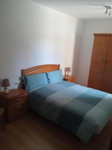 1 dormitorio con cama azul y cabecero de madera en Apartamento Casa Leonora, en Panticosa