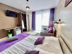 a bedroom with a large bed with purple pillows at Dworek Karwia Wiosenna 8 in Karwia