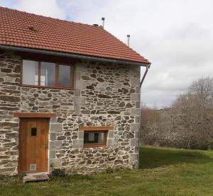 une maison en pierre avec une porte marron et des fenêtres. dans l'établissement La Vieille Maison aux Canards, à Neuvic-Entier
