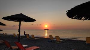 un grupo de sillas y sombrillas en una playa con puesta de sol en Camping Mitikas and Bungalows, en Plaka Litóchoro