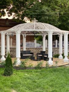 a white gazebo with chairs and tables in a yard at Elena in Krushuna