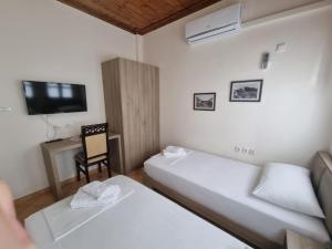Habitación con 2 camas, TV y silla. en Romeo's Guest House en Berat