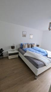 a white bedroom with a large bed and a table at Moderne gemütliche Ferienwohnung in Friedrichshafen in Friedrichshafen