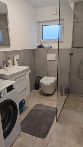 y baño con lavabo y lavadora. en Moderne gemütliche Ferienwohnung in Friedrichshafen, en Friedrichshafen