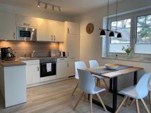 a kitchen with white cabinets and a wooden table and chairs at Min Droom Usedom in Zirchow