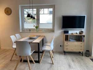 a dining room with a table and chairs and a tv at Min Droom Usedom in Zirchow