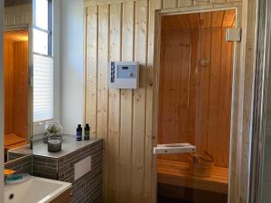 a bathroom with a wooden wall with a sink and a shower at Min Droom Usedom in Zirchow +25 photos
