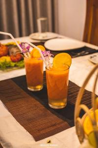 three glasses of orange juice sitting on a table at Bright Waves Villa in Bentota
