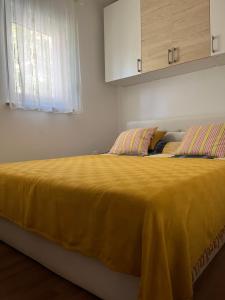 a bedroom with a bed with a yellow blanket on it at Holiday House Sanja Private Terrace BBQ in Peaceful Surroundings in Medulin