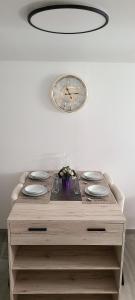 a table with plates and a clock on a wall at Appartement T2 confortable in Pierrelaye