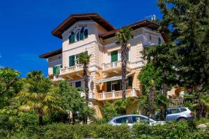 a yellow building with palm trees in front of it at Villa Salus, Apartment Maruna in Opatija