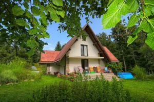 une petite maison blanche avec un toit rouge dans l'établissement Sanjska Hiša Vojsko, à Idrija