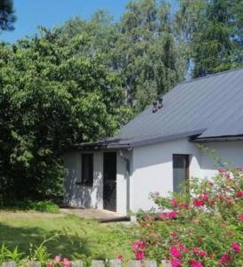 a white house with a black roof and some flowers at Dom na Podlasiu in Klepacze