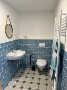 a blue tiled bathroom with a sink and a toilet at Stadthaus Usedom in Usedom Town