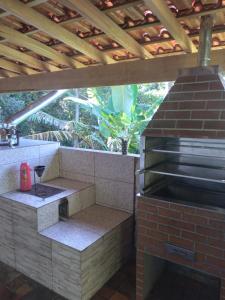 a outdoor kitchen with a brick oven with a roof at Chácara Cantinho da Paz in Ibiúna
