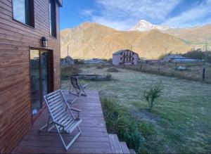 two chairs sitting on a deck with mountains in the background at T&M Timeless memories in Kazbegi