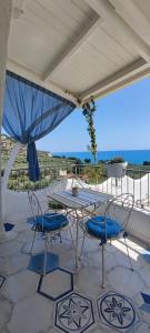 einen Tisch und Stühle auf einer Terrasse mit Meerblick in der Unterkunft Dimora Mediterranea in Mattinata