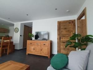 a living room with a couch and a wooden cabinet at Les rives de la jamagne in Gérardmer