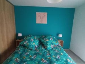 a blue bedroom with a bed with a green comforter at Les rives de la jamagne in Gérardmer