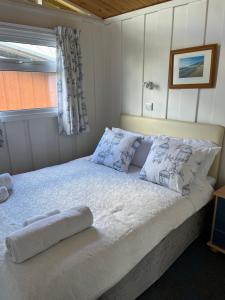 a bedroom with a white bed with pillows and a window at Chalet 31 in Seaton