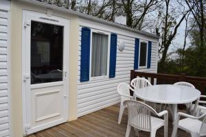 a white shed with a table and chairs on a deck at Camping du Creulet in Crouay