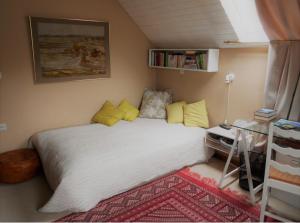 - une chambre avec un lit blanc et des oreillers jaunes dans l'établissement Chez Huguette, à Profondeville