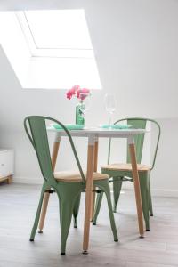 a glass table and two green chairs with wine glasses at @ LOFT COCOONING @ Proche gare & centre historique in Brive-la-Gaillarde