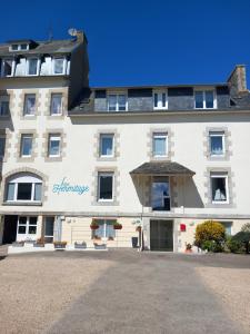 - un grand bâtiment blanc avec un panneau dans l'établissement Logis Hermitage, à Perros-Guirec